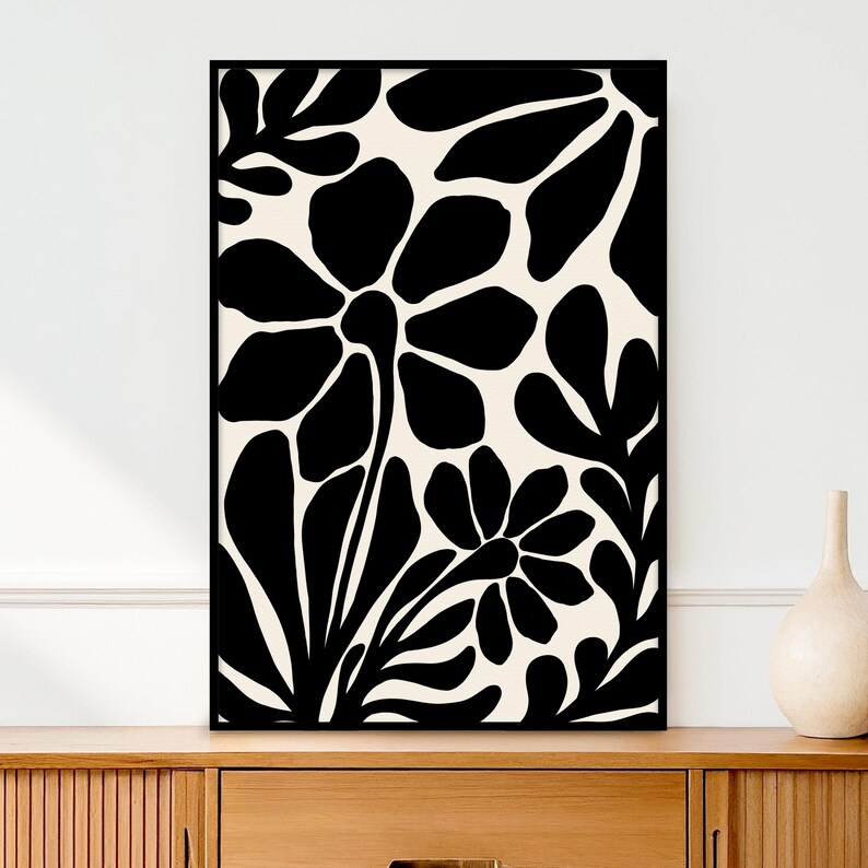 May include: Black and white abstract floral print with large stylized flowers and leaves. The print has a minimalist aesthetic and would be a great addition to any modern home.