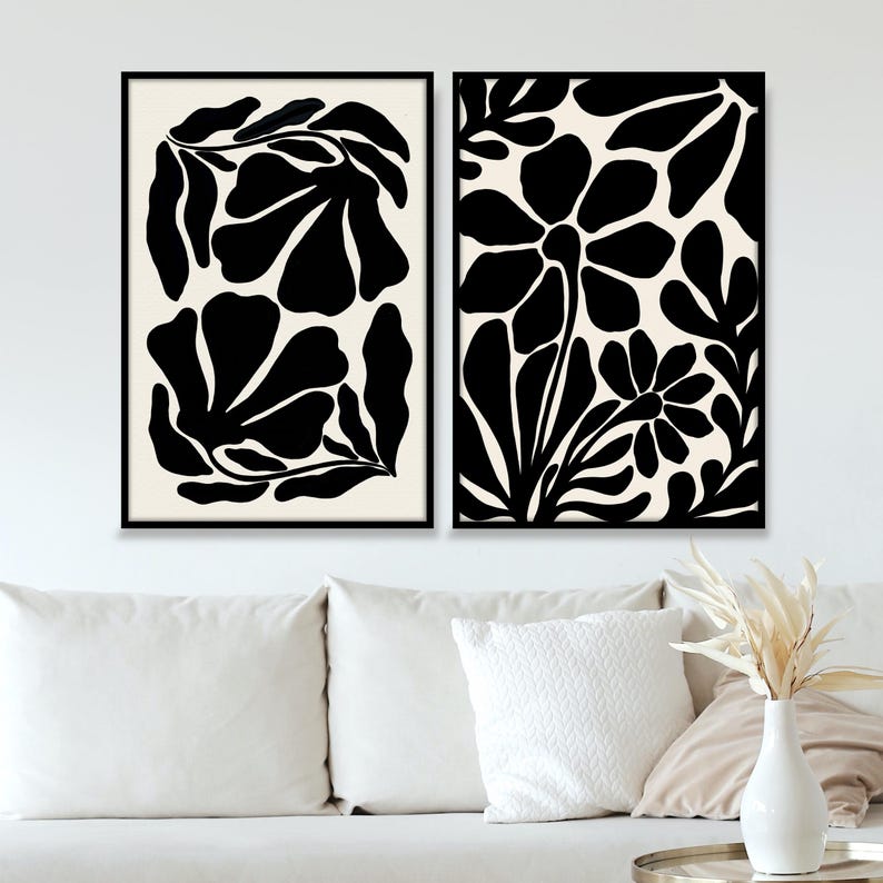 May include: Two black and white abstract floral prints with a minimalist design. The prints feature bold, stylized flowers and leaves.