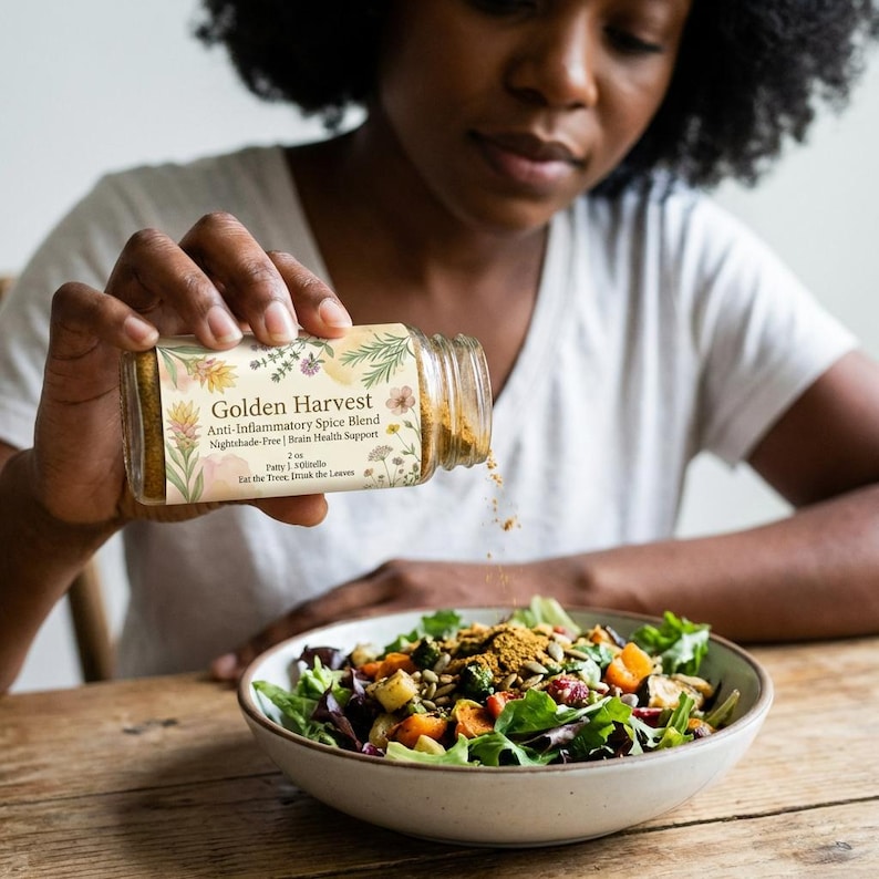 以下が含まれることがあります： ゴールデンハーベスト抗炎症スパイスブレンドをサラダに振りかける様子。スパイスブレンドは、花柄のラベルが付いた透明なガラス瓶に入っています。サラダには、ミックスグリーン、ニンジン、種が含まれています。瓶のテキストには「Eat the Tree, Drink the Leaves」と書かれています。
