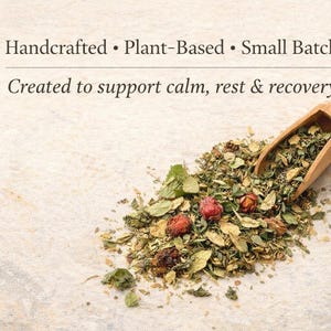 Pu&ograve; includere: Un cucchiaio di legno pieno di un mix di erbe e fiori secchi, tra cui bacche rosse e foglie verdi, &egrave; appoggiato su una superficie chiara. Il testo recita: Handcrafted, Plant-Based, Small Batch. Created to support calm, rest & recovery.