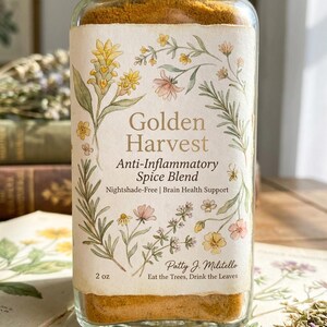 以下が含まれることがあります： 「Golden Harvest Anti-Inflammatory Spice Blend」とラベルされたガラス瓶。ラベルには、黄色、ピンク、緑色の花のイラストが描かれています。瓶には金色のスパイスブレンドが入っており、57グラムと表示されています。