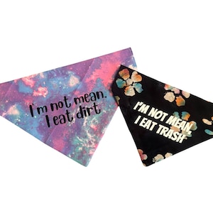 May include: Two dog bandanas with tie-dye patterns. One bandana is pink and blue with the text "I'm not mean, I eat dirt". The other bandana is black with the text "I'm not mean, I eat trash" in white.