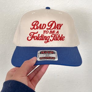 Buffalo Football, Bad day to be a folding table, Football tailgating, fall football season hats, 3d puff embroidery, football gift, game day outfit, customizable hat, puff print, bil football, buffalo bil funny hat, folding hat humor, football humor, football buffalo print 3d puff "bad day to be a folding table" embroidered trucker hat for women, gift for men, gift for bil fans, gift for fans in buffalo new york, funny embroidery for fans