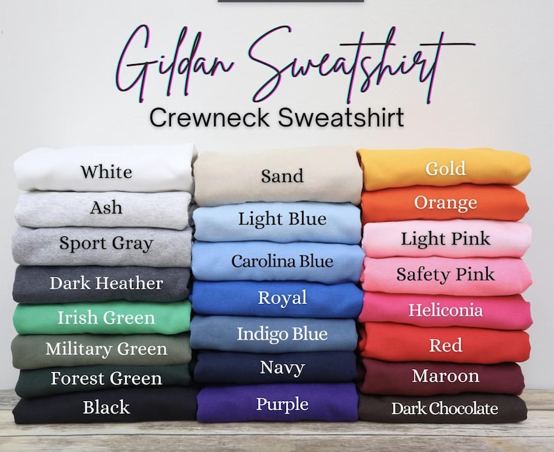 Puede incluir: Una pila de sudaderas Gildan de cuello redondo en varios colores, incluyendo blanco, ceniza, gris deportivo, gris oscuro y negro. Otros colores incluyen verde irland&eacute;s, verde militar y verde bosque. La imagen tambi&eacute;n muestra arena, azul claro, azul Carolina, dorado, naranja y rosas.