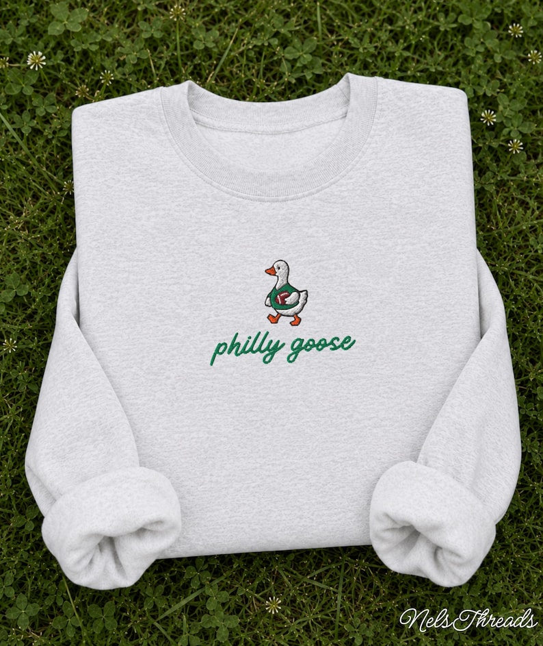 May include: A light gray crewneck sweatshirt featuring an embroidered graphic of a white goose wearing a green jersey and holding a brown football. Below the goose, the text "philly goose" is embroidered in a green cursive script font.
Philadelphia Football, Embroidered Crewneck Sweatshirt, T-Shirt Embroidery, Philly Goose, Silly Goose
philly goose philly goose sweatshirt philadelphia philly goose shirt retro philadelphia designs philly crewneck