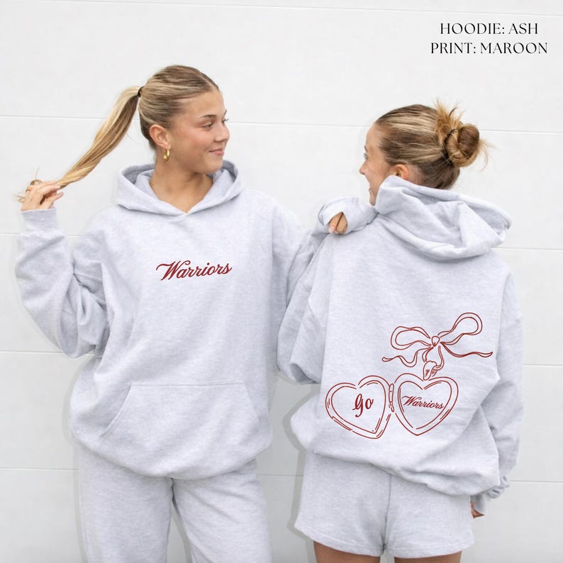 Puede incluir: Sudadera con capucha gris claro con la palabra "Warriors" en escritura granate en la parte delantera. La parte trasera presenta un dise&ntilde;o de medall&oacute;n en forma de coraz&oacute;n granate con "Go Warriors". Parte de un conjunto a juego.