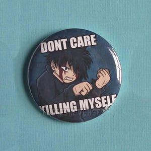 Puede incluir: Un botón redondo con una ilustración estilo anime de un personaje con cabello oscuro y camisa oscura. El texto DONT CARE está impreso en la parte superior y KILLING MYSELF en la parte inferior en letras mayúsculas blancas y negritas.