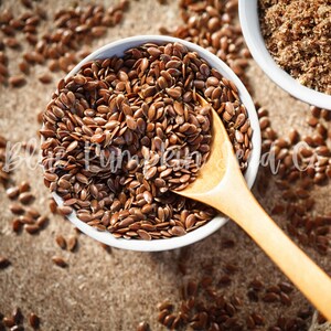 A wooden spoon retrieving flax seeds from a container.
