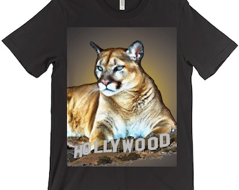 Puede incluir: Camiseta negra con un gráfico de un puma frente al letrero de Hollywood.
