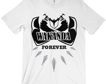 Puede incluir: Camiseta blanca con un gráfico negro de dos brazos cruzados con el texto "Wakanda Forever" debajo. El gráfico está rodeado de seis diamantes negros y grises.