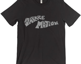 Puede incluir: Camiseta negra con un estampado "Sparkle Motion" gris plateado en la parte delantera.