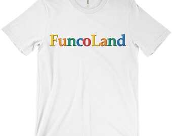 Puede incluir: Camiseta blanca con la palabra "FuncoLand" impresa en letras coloridas en el pecho. El texto es amarillo, naranja, verde, azul, rojo y amarillo. La camiseta está hecha de un material suave.