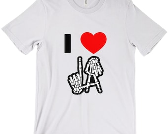 Puede incluir: Camiseta blanca con un gráfico negro que dice "I love LA" con un corazón rojo y manos de esqueleto formando las letras LA.