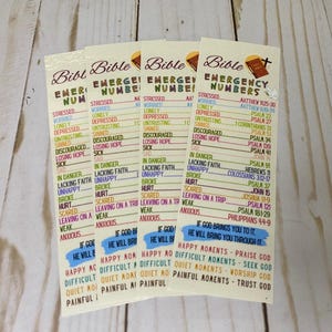 May include: Four Bible Emergency Numbers bookmarks. Each bookmark features a list of emotional states and corresponding Bible verses. The bookmarks have a cream background with black and colored text.