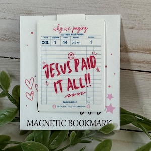 May include: A white magnetic bookmark featuring a blue grid design resembling a bill. The text reads why we paying, COL 1 14 Jesus 1, JESUS PAID IT ALL!!, PAID IN FULL!, and THANK YOU. TELL YOUR FRIENDS. It includes pink hearts, stars, and smiley faces.
