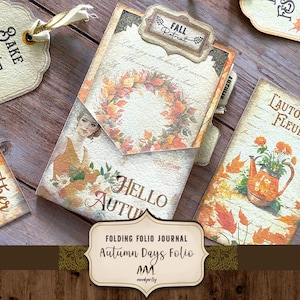May include: A folding folio journal titled Autumn Days Folio featuring a central pocket with a wreath of orange and red leaves, a portrait of a person, and the text Hello Autumn. Includes tags with text Bake Fest, Gather, and L'Automne Fleur.
