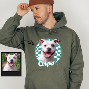 A man wearing a green hoodie with a graphic of a dog and the name "Cooper" printed on it.