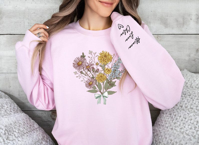a woman wearing a pink sweatshirt with flowers on it