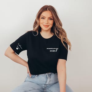 a woman sitting on a stool wearing a black shirt