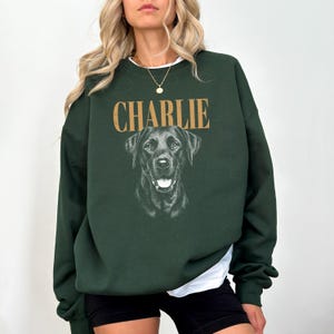 A woman wearing a green sweatshirt with a black dog printed on it.