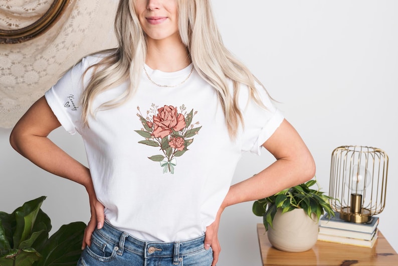 a woman with blonde hair wearing a white t - shirt with a rose on it