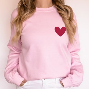 a woman wearing a pink sweater with a red heart on it