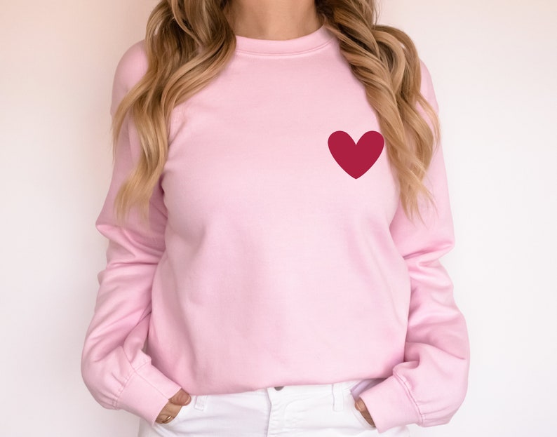 a woman wearing a pink sweater with a red heart on it