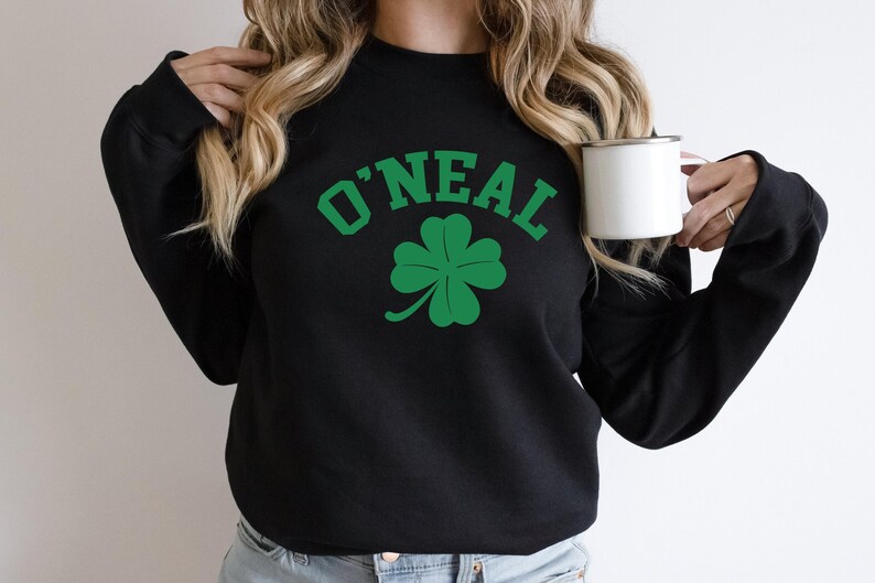a woman holding a cup of coffee and wearing a sweatshirt