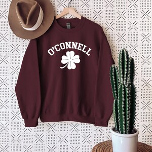 a maroon sweatshirt with a shamrock on it and a hat hanging on a wall