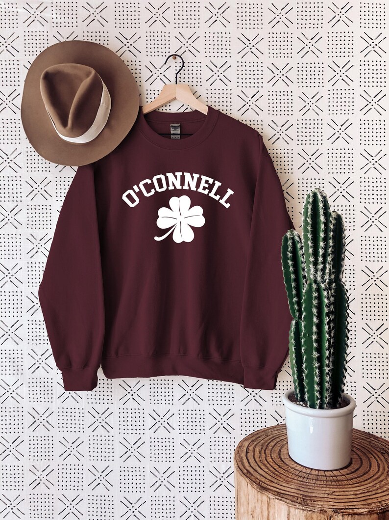 a maroon sweatshirt with a shamrock on it and a hat hanging on a wall