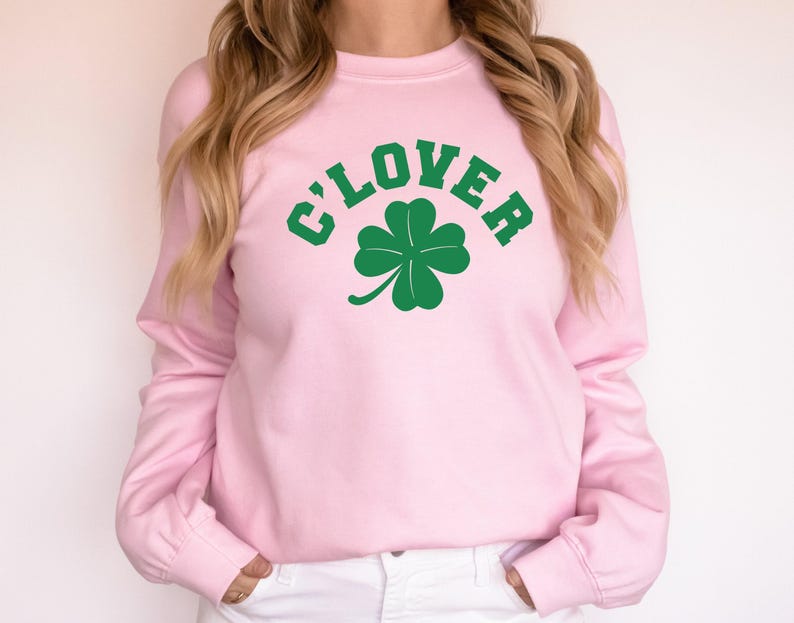 a woman wearing a pink sweater with a clover on it