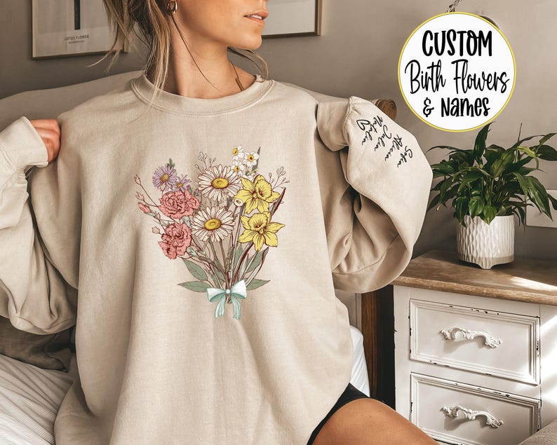 a woman sitting on a bed wearing a sweatshirt with flowers on it