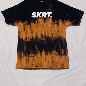 May include: Black and brown tie-dye t-shirt with the word "SKRT." printed in white on the front.