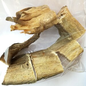 May include: Dried fish pieces in a clear plastic bag. The fish is light brown and has a rough texture.