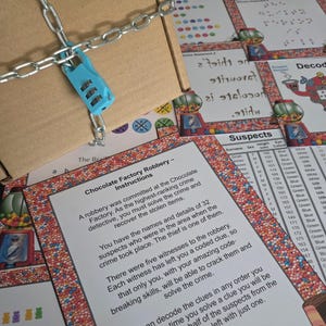 Pu&ograve; includere: Una scatola di cartone fissata con una catena di metallo argentato e un lucchetto a combinazione azzurro a tre cifre, posizionata sopra fogli di gioco stampati intitolati Chocolate Factory Robbery, con liste di sospettati e grafiche a tema.