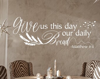 May include: A dining room with a round wooden table and four zebra-print chairs. The wall behind the table has a white vinyl decal with the text "Give us this day our daily Bread - Matthew 6:11".