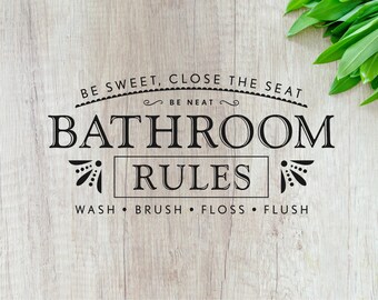以下が含まれることがあります： 明るい木製の背景に、「BE SWEET, CLOSE THE SEAT BE NEAT BATHROOM RULES WASH BRUSH FLOSS FLUSH」というテキストが書かれた白黒の看板です。