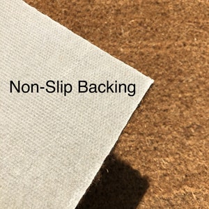 K&ouml;nnte beinhalten: Nahaufnahme eines wei&szlig;en, strukturierten Materials mit der Aufschrift "Non-Slip Backing" vor einem braunen, faserigen Hintergrund. Das wei&szlig;e Material ist abgewinkelt und zeigt seine Kante und die kontrastierende Textur des braunen Hintergrunds.