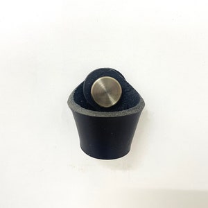 May include: A black leather pull with a silver metal knob. The pull is designed to be used on a drawer or cabinet.