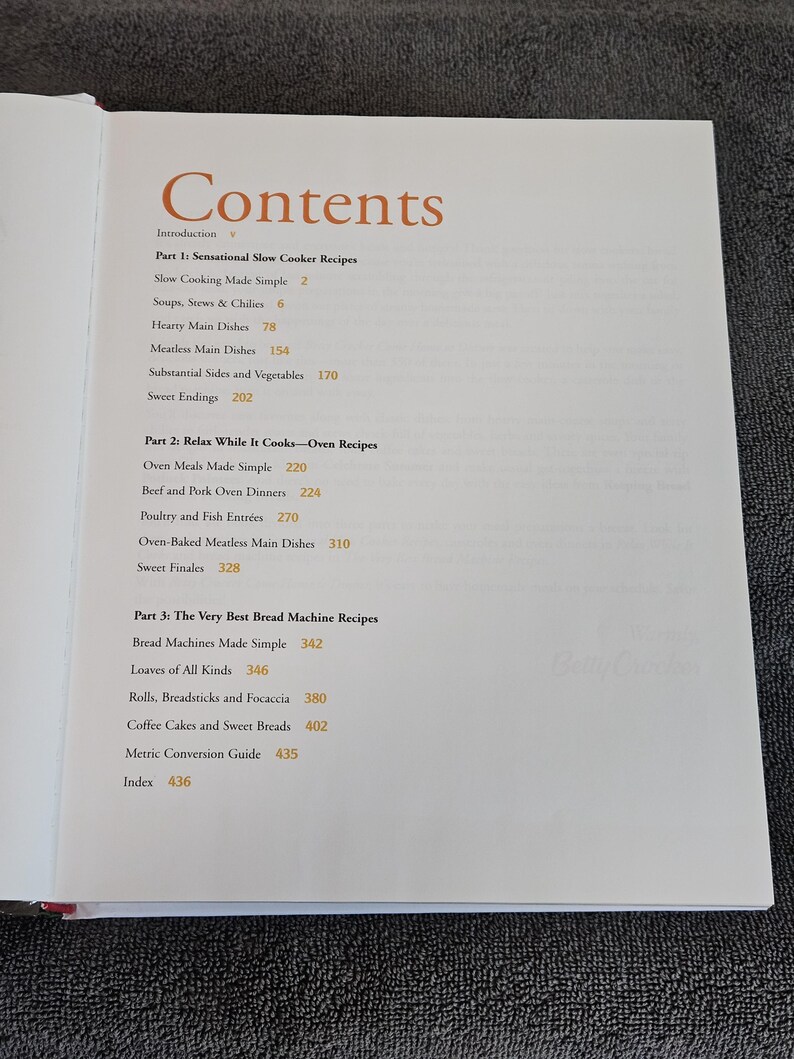May include: Open cookbook page with the title "Contents" in a warm orange font. The table of contents lists recipes for slow cooker, oven, and bread machine dishes. The book includes a metric conversion guide and an index.