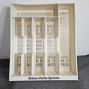 May include: Off-white plastic cutlery tray with multiple compartments for organizing silverware. The tray has a rectangular shape with slotted dividers and the text "Knives-Forks-Spoons" printed on the front.