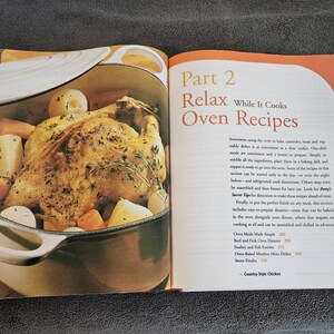 May include: Open cookbook page with a roasted chicken and vegetables in a pot. The text reads "Part 2 Relax While It Cooks Oven Recipes". The image is a close-up of a cooked chicken with potatoes and carrots.