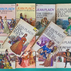 May include: A selection of vintage Jean Plaidy paperback books, including titles such as "The Princess of Celle," "Queen in Waiting," and "The Sixth Wife." The covers display illustrations of historical scenes and figures, typical of the period.