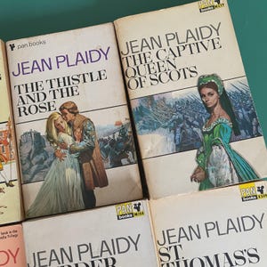 May include: A selection of vintage Jean Plaidy paperback books. The covers display illustrations of historical scenes and figures, including titles such as "The Thistle and the Rose" and "The Captive Queen of Scots". Published by Pan Books.