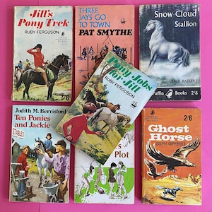 Puede incluir: Una colección de libros infantiles vintage con cubiertas coloridas. Los títulos incluyen "Jill's Pony Trek", "Three Jays Go to Town" y "Snow Cloud Stallion". Los libros presentan ilustraciones de caballos y niños, sobre un fondo rosa.