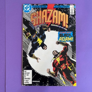 May include: A vintage comic book cover featuring Shazam and Black Adam in a dynamic clash. The cover art showcases vibrant colors, with Shazam in red and Black Adam in black, set against a starry background. Text includes "Shazam! Beginning" and "Clash with Black Adam!"