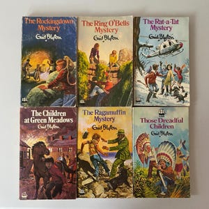 Può includere: Una collezione di sei libri per bambini vintage di Enid Blyton. Le copertine presentano illustrazioni colorate e titoli come "The Rockingdown Mystery" e "The Ring O'Bells Mystery". I libri sono disposti in due file da tre.