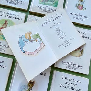 Puede incluir: Una colección de libros infantiles vintage de Beatrix Potter. Los libros presentan ilustraciones de Peter Rabbit, Jemima Puddle-Duck y otros personajes queridos. Las portadas son de varios tonos de azul, verde y amarillo.