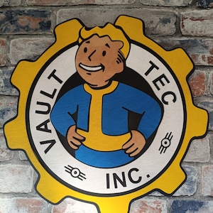 May include: A circular wooden wall sign shaped like a yellow gear featuring the Vault-Tec mascot. The design includes a blue and yellow jumpsuit-clad character in the centre, with the text VAULT-TEC INC. printed in black along the white border.