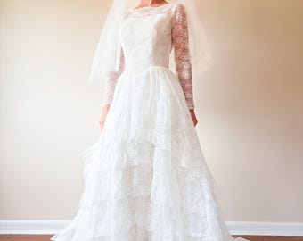 Robe de mariée princesse en dentelle blanche à plusieurs niveaux des années 60 / Manches en dentelle transparente / Taille basque / Jupe évasée avec train / Voile couronne / Petite taille